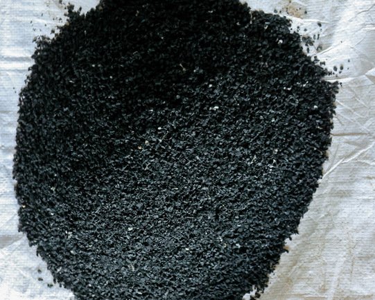Close view of black recycled rubber granules on a white sack