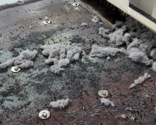 Grey textile fibre collecting on the separation deck during tyre recycling